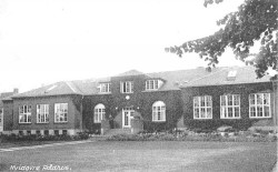 Med tiden voksede landsbyskolen til dobbelt størrelse, og med den bagved liggende tilbygning, fungerede den som kommunekontor og rådhus frem til midten af 1950'eme.
(Postkort 1930’eme HLA)