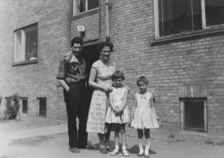 Pia står med sine forældre og sin barndomsveninde, Lone foran opgangen i nr. 128